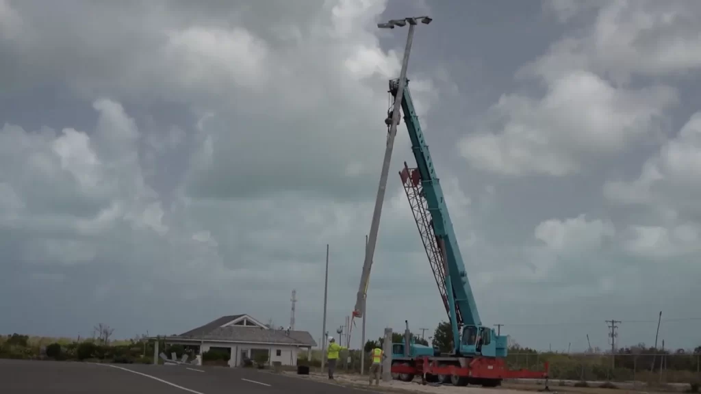 Installed 15.2 m LED apron lighting pole standing at Burton–Nibbs International Airport, Barbuda, with the terminal building in the background